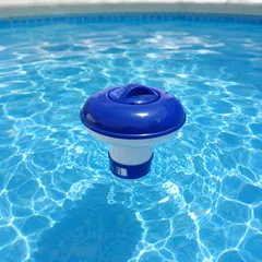 Un dozator plutitor din plastic alb-albastru pentru tablete de clor plutește pe suprafața apei albastre și limpezi dintr-o piscină, creând u
